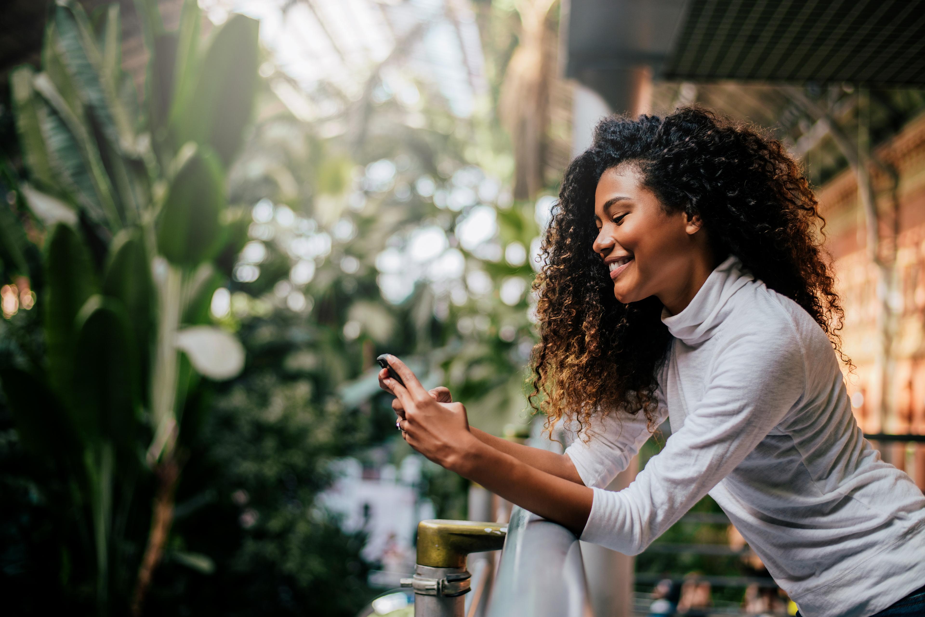 Woman leaning on a railing and looking at her phone